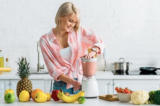 The girl prepares smoothies to lose weight in a blender